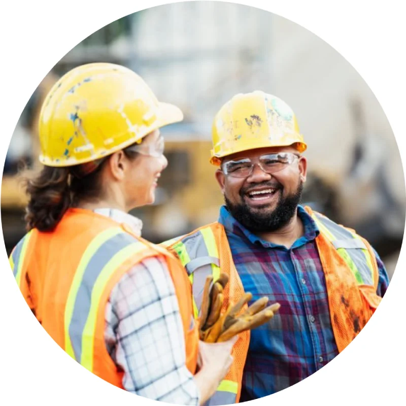 Construction workers laughing, safety helmets, reflective vests.