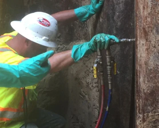 Worker drilling with equipment in hardhat and safety gear.