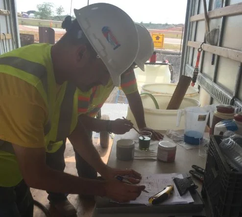 Worker in hard hat conducting paint inspection.