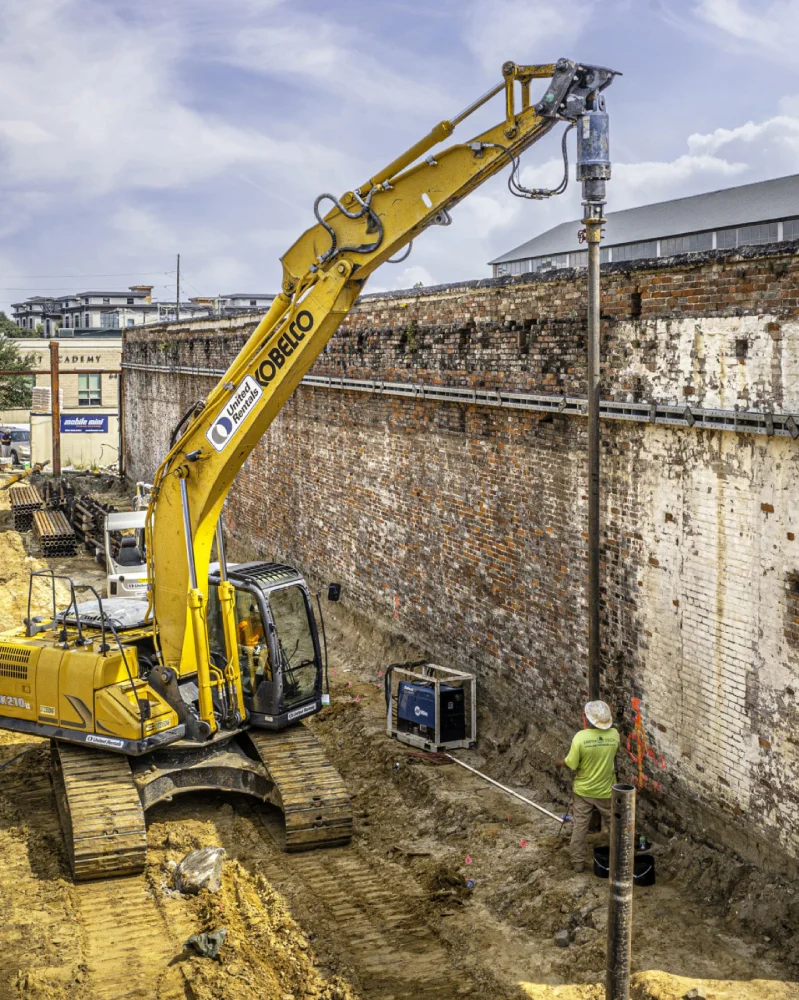 Excavator and worker at construction site.