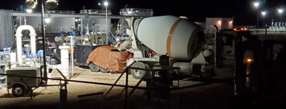 Nighttime industrial site with cement mixer and equipment.