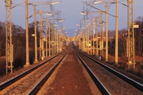 Empty railway tracks at dusk with overhead lines.