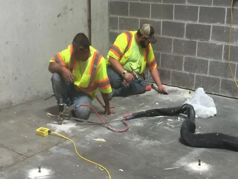 Workers installing flooring in construction site.