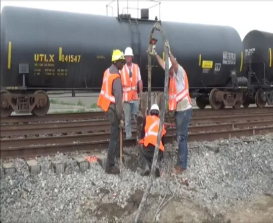 Railroad workers repairing track with tools.