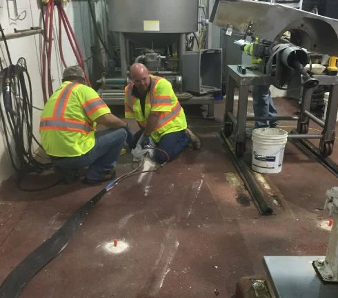 Workers in hi-vis vests repairing machinery.