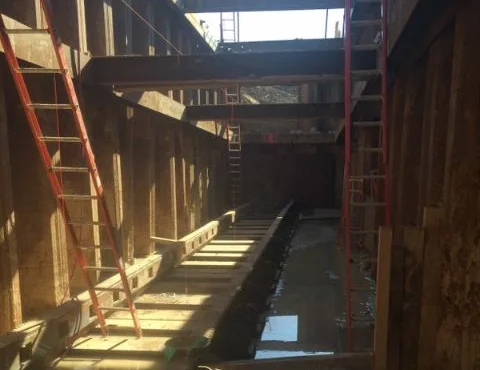 Construction site trench with scaffolding and shadows.