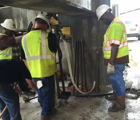 Construction workers operating machinery at a site.