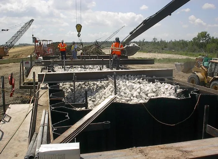 Construction workers pouring concrete at industrial site.