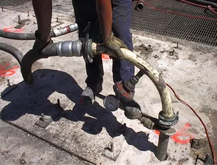 Worker handling industrial concrete pumping hoses.