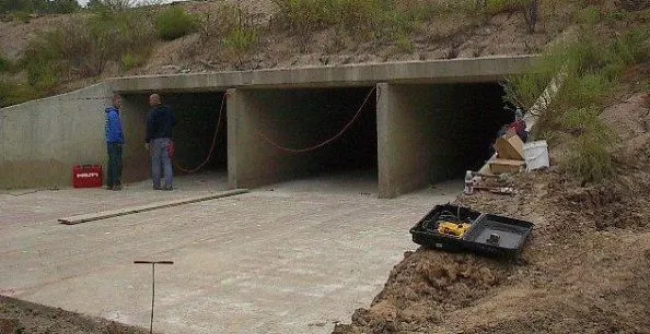 Wildlife underpass construction with workers and equipment.