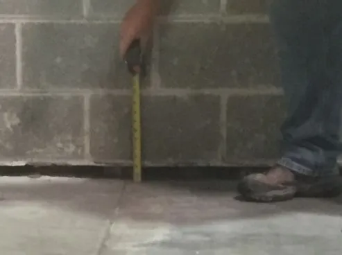 Person measuring floor with tape measure.