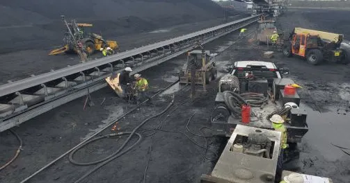 Workers repairing conveyor belt at industrial coal mine.