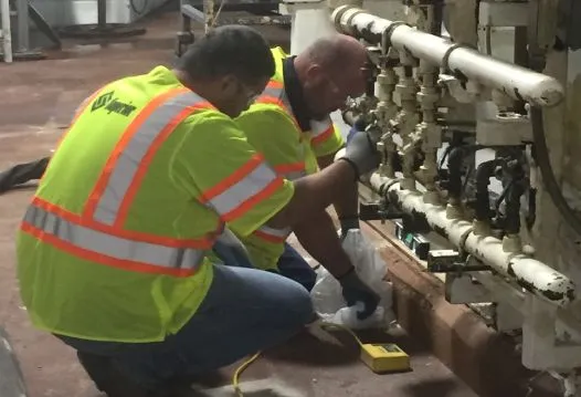 Workers in high-visibility vests repairing machinery.