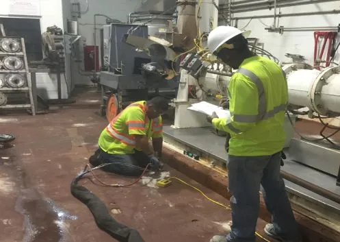 Workers in safety gear inspecting equipment.