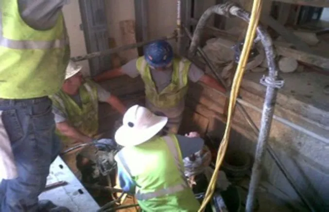 Construction workers in safety gear at a worksite.