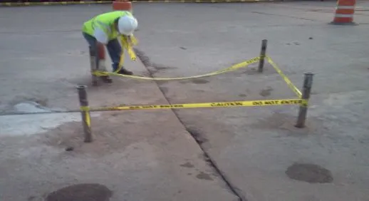 Worker setting up caution tape at construction site.