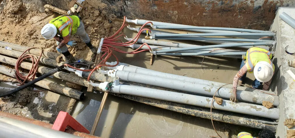 Workers installing underground pipes at construction site.