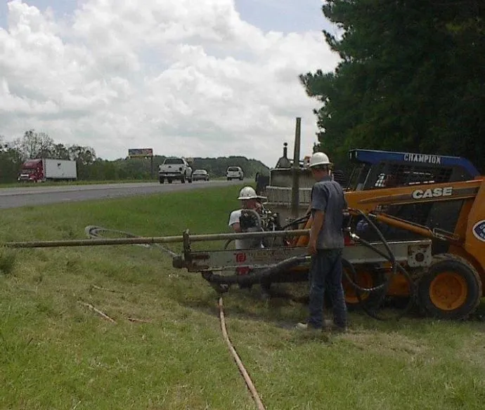 Workers operating machinery by roadside