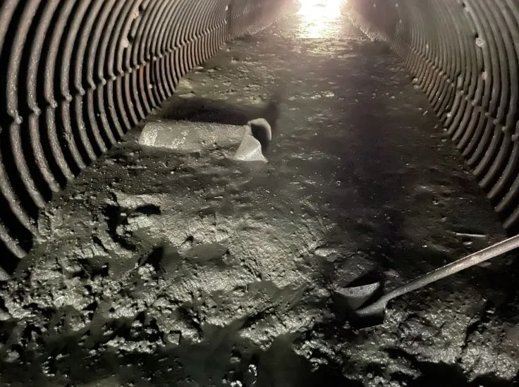 Dark corrugated tunnel with light at end.