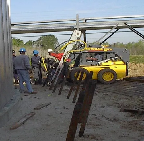 Construction workers using a skid-steer loader on site.
