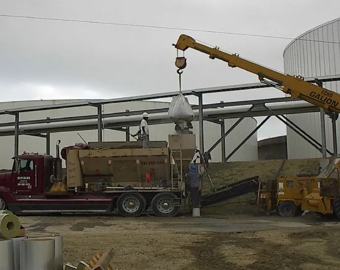 Construction workers operating crane and unloading truck materials.