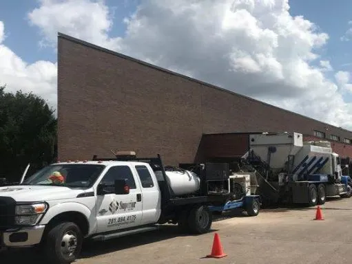 Industrial cleaning truck near brick building.