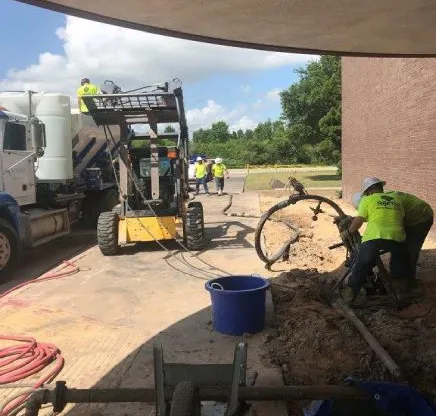 Construction workers operating machinery outdoors.