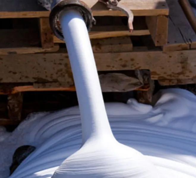 Flowing white foam from industrial machinery.