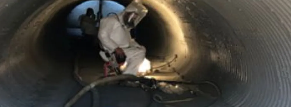 Worker welding inside industrial pipe.