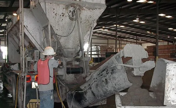 Worker operating concrete pump indoors at construction site.