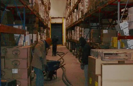 Workers organizing boxes in a warehouse aisle.