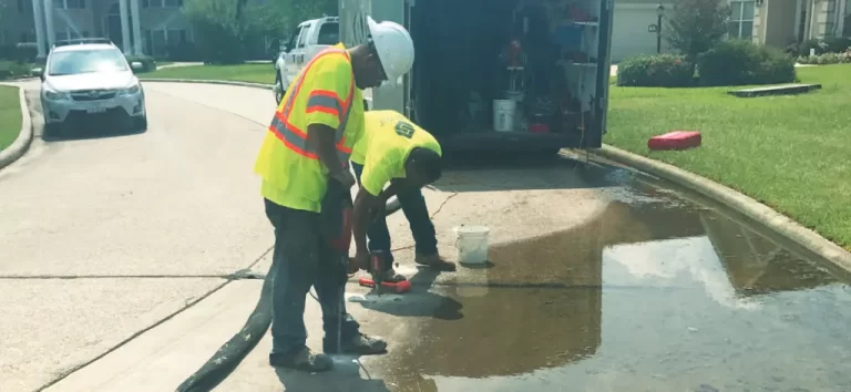 Workers inspecting water leakage on residential street.