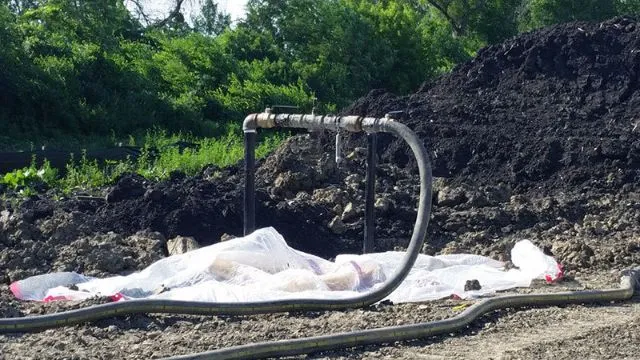 Irrigation pipe on soil heap at construction site.