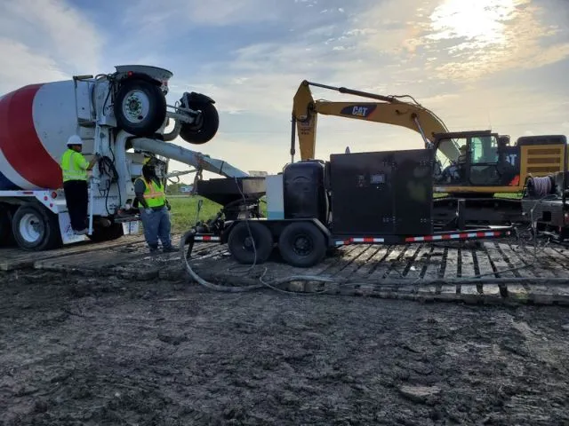 Construction workers with machinery at a worksite.