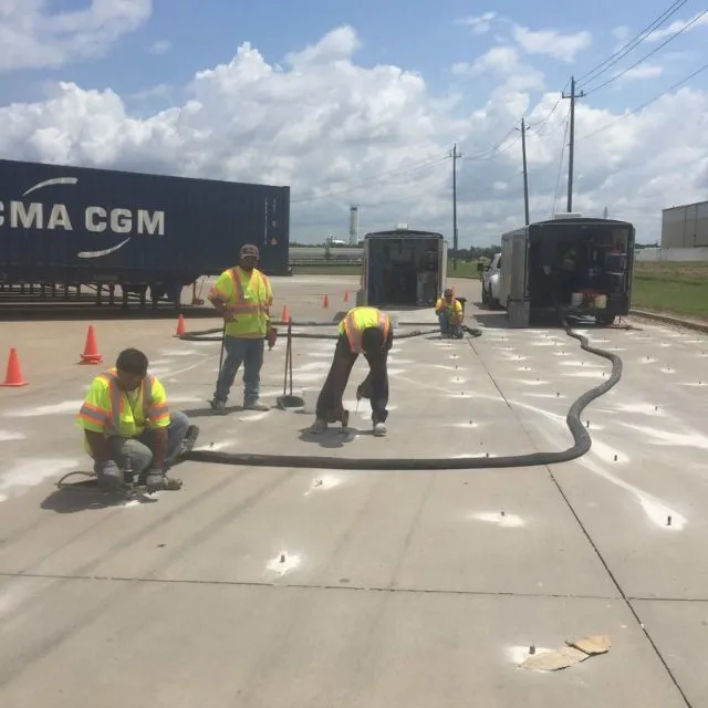 Workers in reflective vests laying cables on pavement.