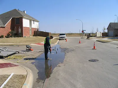 Worker pressure washing a suburban street.