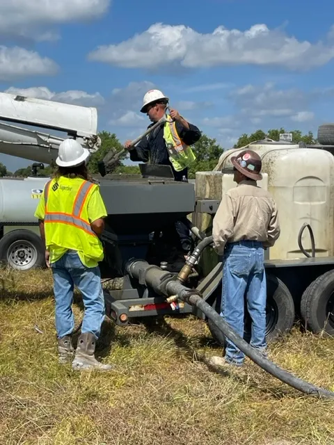 Workers operating concrete pumping machinery outdoors.