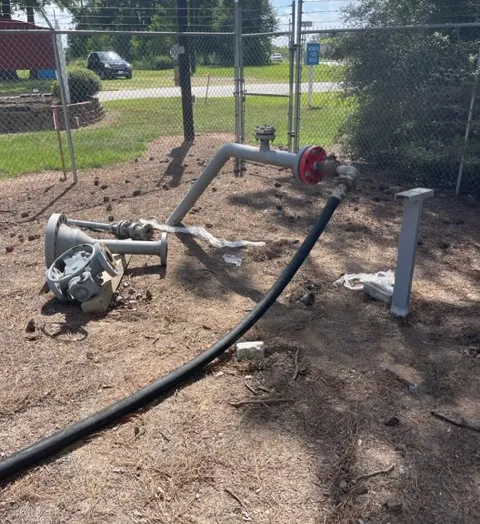 Industrial piping and motor outdoors near fence.