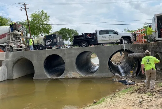 Workers installing culverts near water.