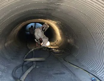 Workers inside a large industrial pipe.