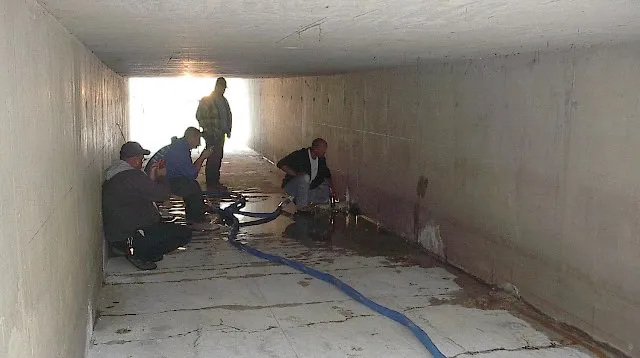 Workers inspecting underground tunnel.