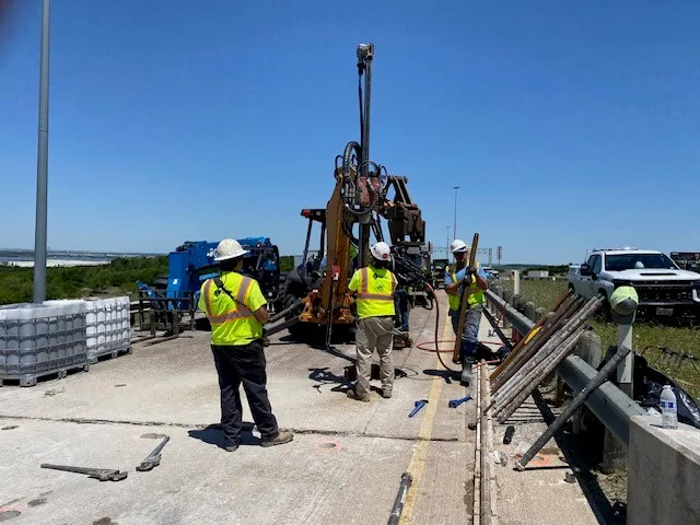 Workers operating drilling machinery on construction site.