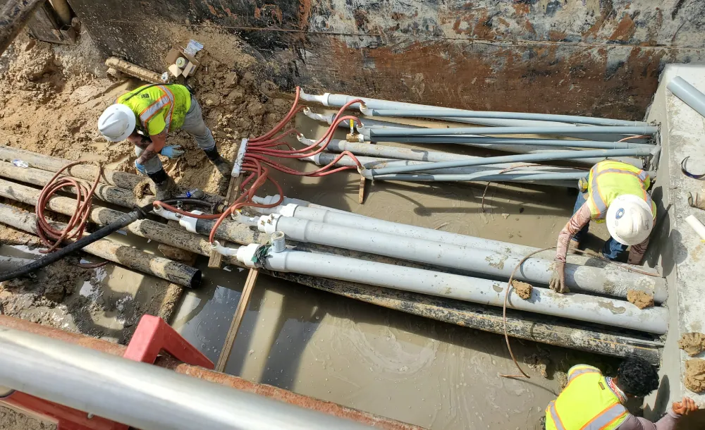 Workers installing underground pipes at construction site.