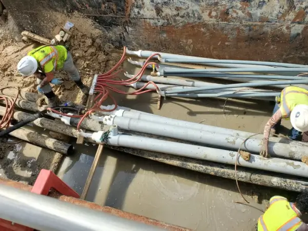 Workers installing underground pipes at construction site.