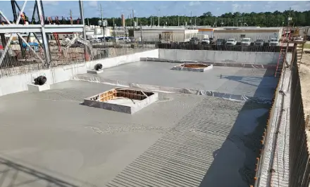 Construction site with freshly poured concrete foundation.