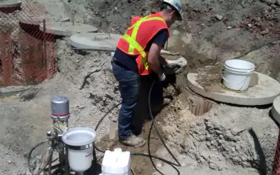 Construction worker using jackhammer at a worksite.