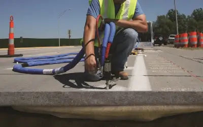 Worker installing cables on road.