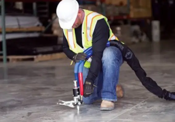 Worker applying sealant on warehouse floor.