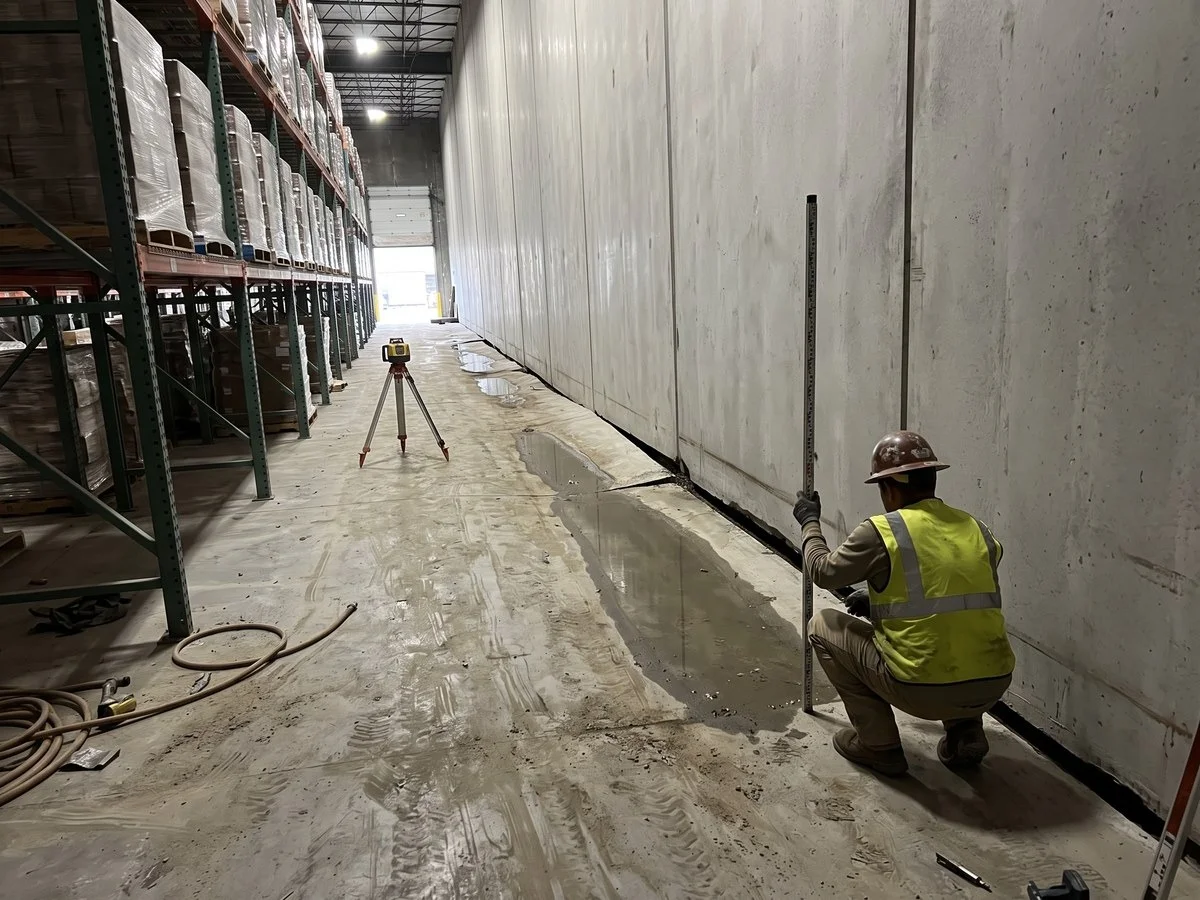Settled pour strip with standing water along the base of tilt-wall panels